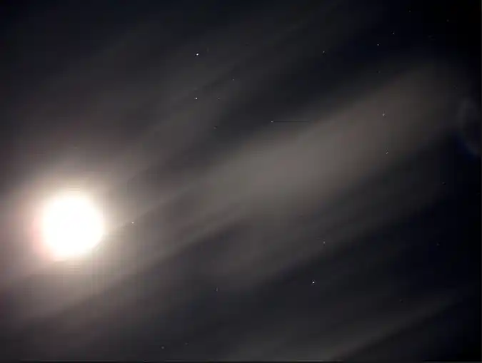 Lune lumineuse perçant à travers des voiles de nuages dans un ciel nocturne étoilé. Illustration du poème « Des espoirs » d’Hervé Gransart.