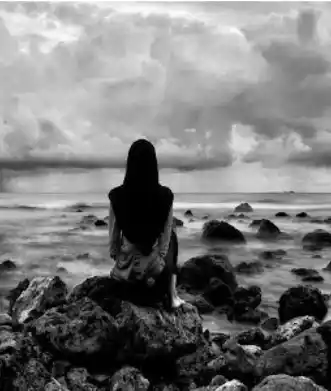 Femme assise de dos sur des rochers face à une mer tourmentée sous un ciel d’orage, en noir et blanc. Illustration du poème « Conte de faits » d’Hervé Gransart.